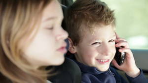 Cute Young Girl Teases - Family traveling while young boy in car backseat playing with mobile phone  - HD stock footage