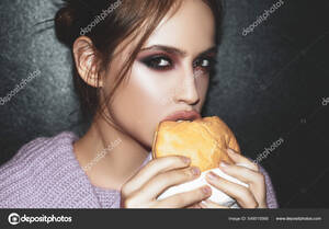 Food Girl Porn - Woman eats a burger, food. Food porn. Teen girls enjoying delicious burgers  in cafe. Beautiful young girl in studio on gray background and perfect  makeup. Stock Photo by Â©Tverdohlib.com 549015568