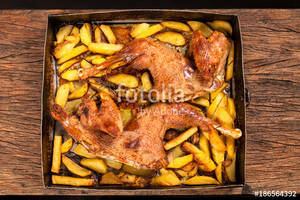 black background porn - High angle view of roast chicken with potatoes on a wooden table. Black  background.