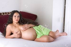 long hair pregnant nude - pregnancy 3 weeks before childbirth. Seminude ethnic Hispanic Latina woman  with long hair lying down