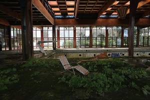 Decay Porn - A lawn chair sits as nature takes over the indoor pool area of Grossinger's  Catskill Resort