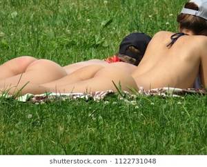 natural nude beach in buttox - Moscow, Russia - June 2018: Young women nudist sunbathing on a green grass,