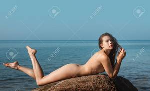 free outdoor nudist beach pics - Naked girl outdoors enjoying nature. Beautiful young nude woman lies on  large stones against the